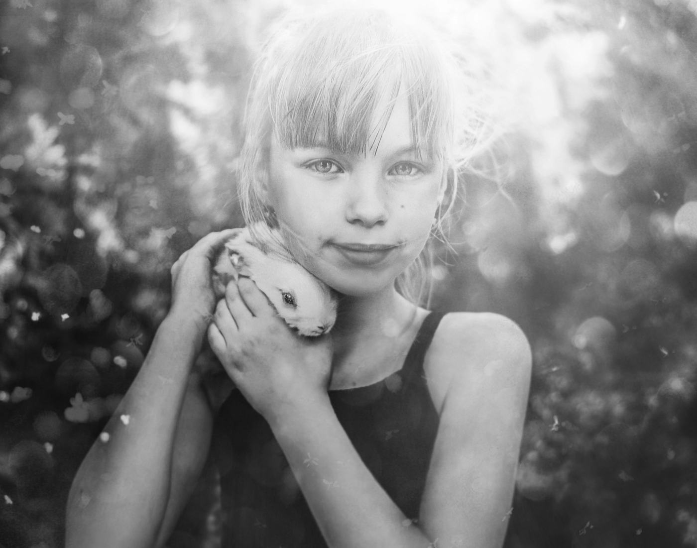 Black and white portrait of a girl cuddling her pet rabbit